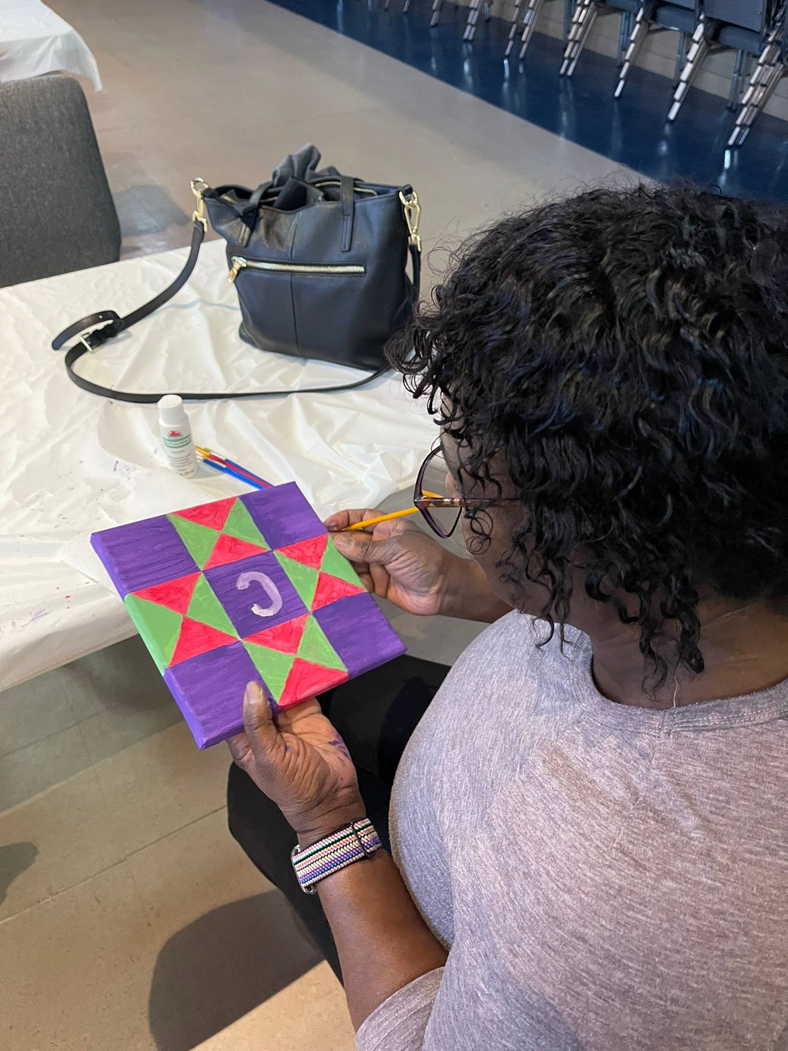 A member painting a barn quilt square at a fellowship event